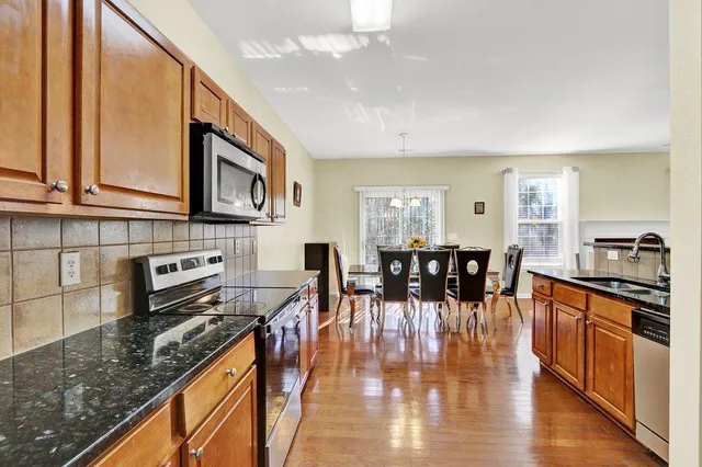 a kitchen with stainless steel appliances granite countertop a stove top oven a sink a dining table and chairs