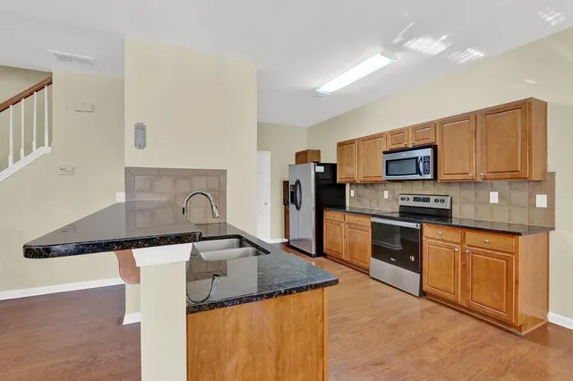 a kitchen with granite countertop a sink a stove top oven and stainless steel appliances