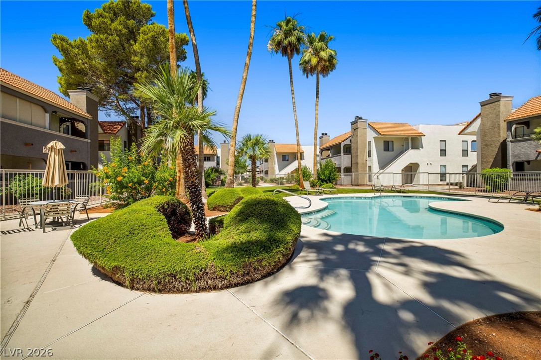 3311 Sunfish Drive, Unit D Henderson, NV 89014 - Photo 9 of 21 Lush landscaping surrounds a sparkling pool, offering a refreshing retreat amidst the residential community.
