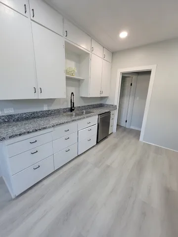 a kitchen with granite countertop white cabinets and white appliances