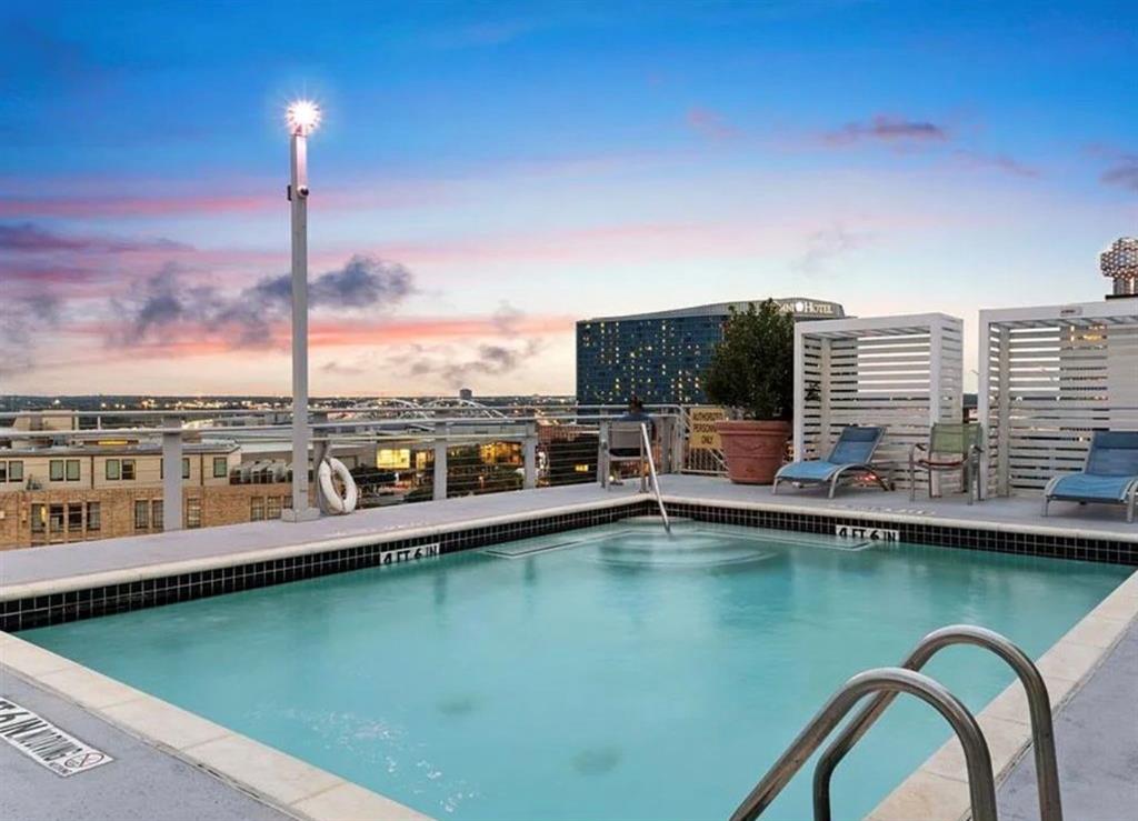 1122 Jackson Street, Unit 514 Dallas, TX 75202 - Photo 33 of 40 Rooftop pool featuring black and white tile coping, stainless steel handrails, and a surrounding concrete deck