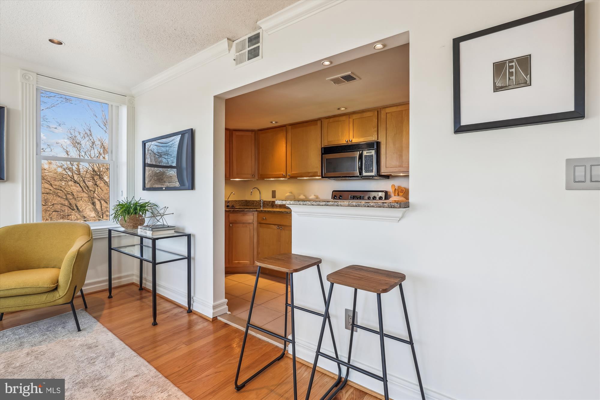 2630 Adams Mill Road Northwest, Unit 209 Washington, DC 20009 - Photo 12 of 47 a kitchen with stainless steel appliances a stove top oven a sink a dining table and chairs with wooden floor