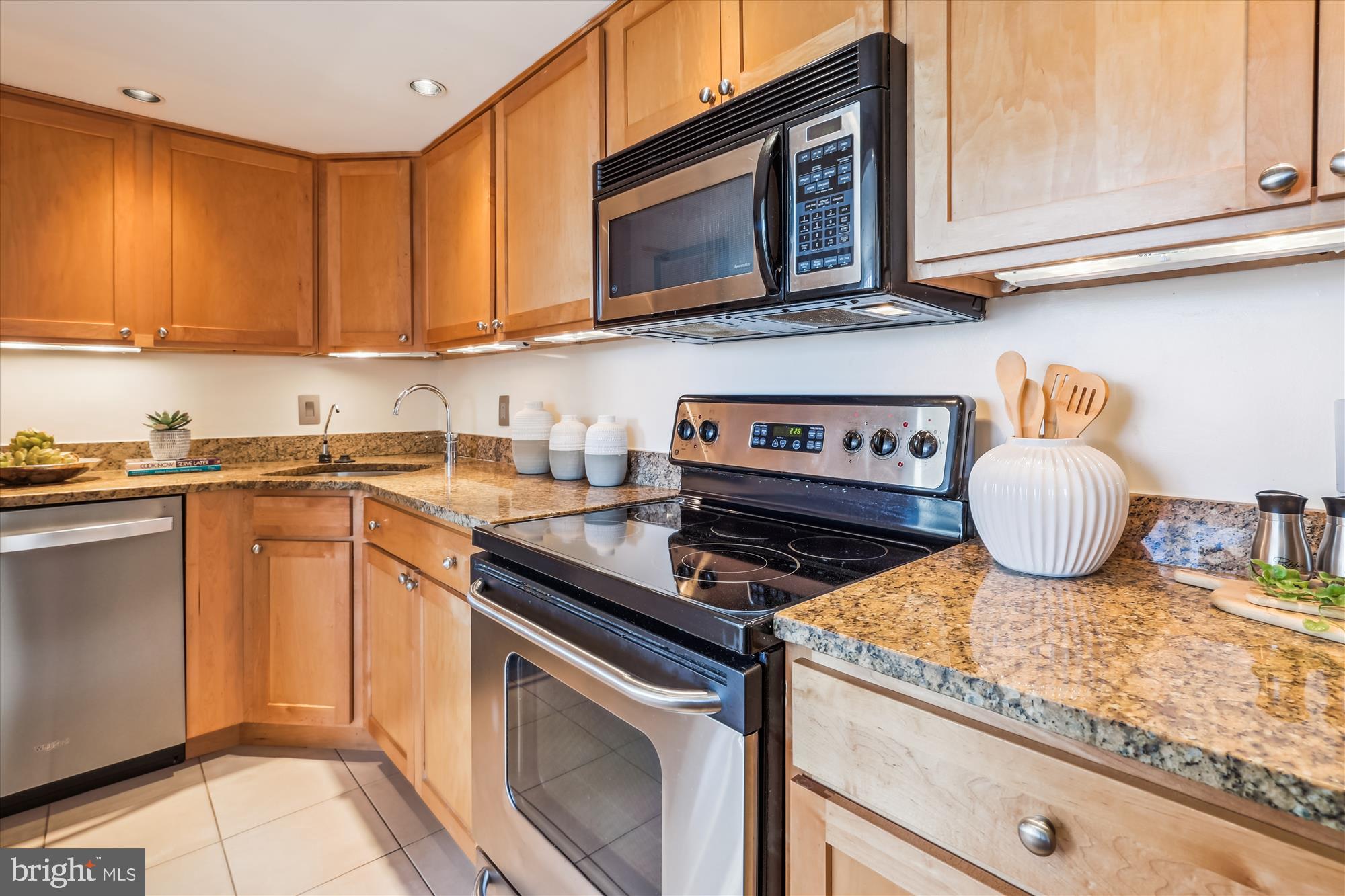 2630 Adams Mill Road Northwest, Unit 209 Washington, DC 20009 - Photo 14 of 47 a kitchen with granite countertop a stove top oven microwave and cabinets