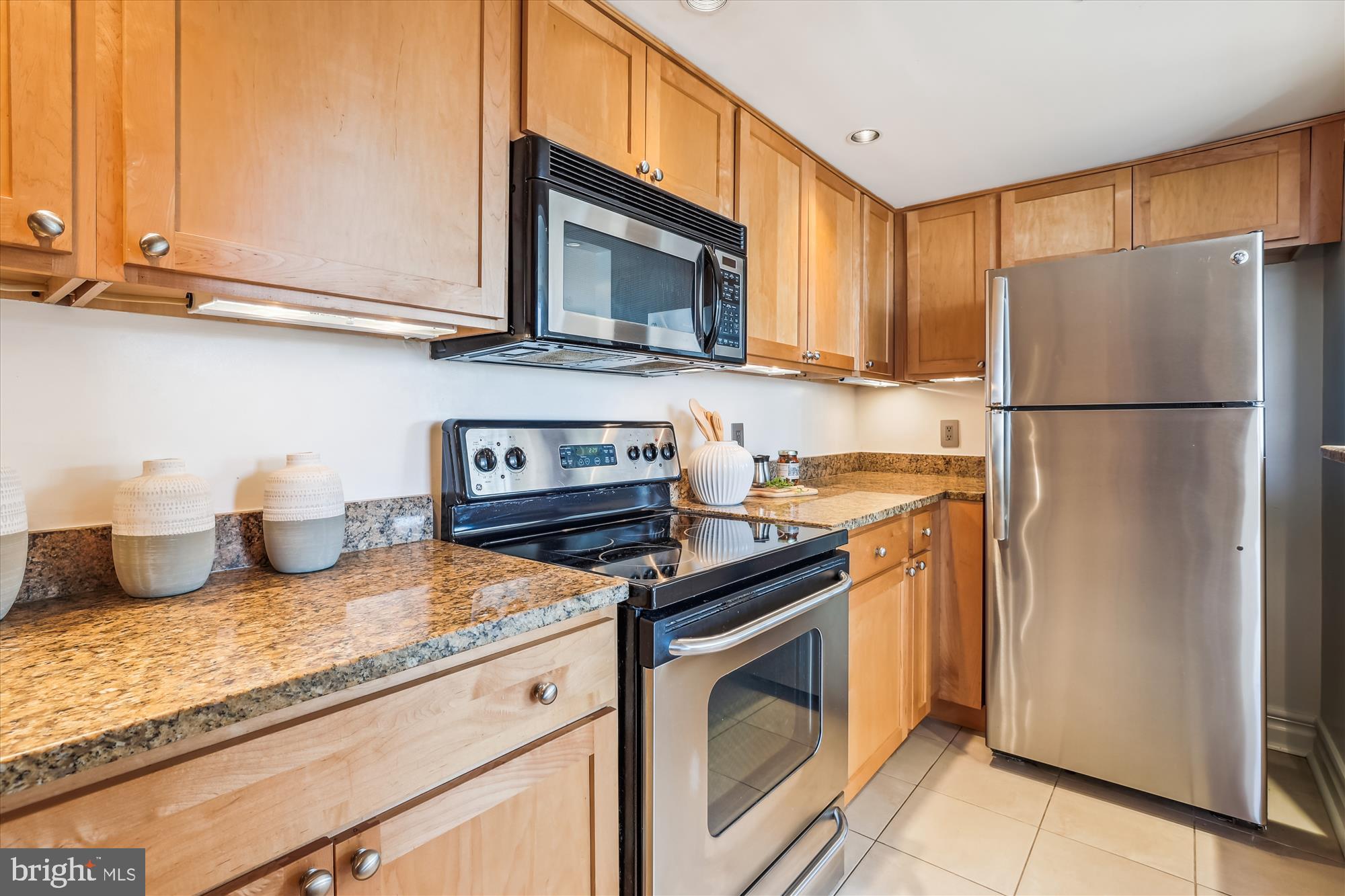 2630 Adams Mill Road Northwest, Unit 209 Washington, DC 20009 - Photo 15 of 47 a kitchen with granite countertop a refrigerator stove and microwave