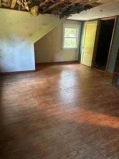 a view of an empty room with wooden floor and closet