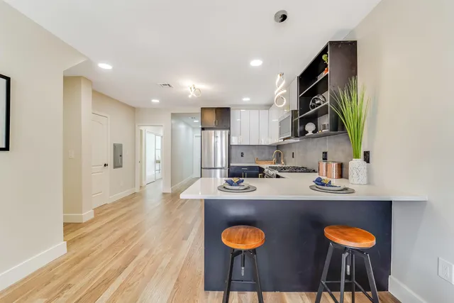 a large kitchen with stainless steel appliances kitchen island granite countertop a refrigerator and a stove top oven