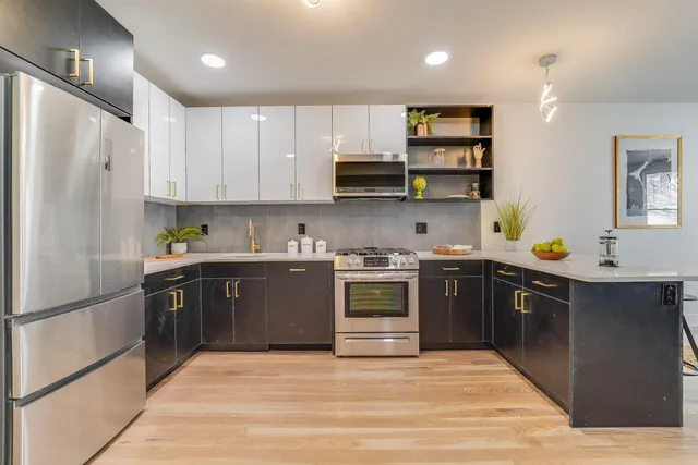 a large white kitchen with lots of counter space a sink appliances and cabinets