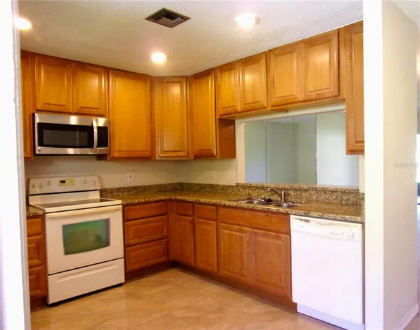 a kitchen with stainless steel appliances granite countertop a stove microwave and cabinets