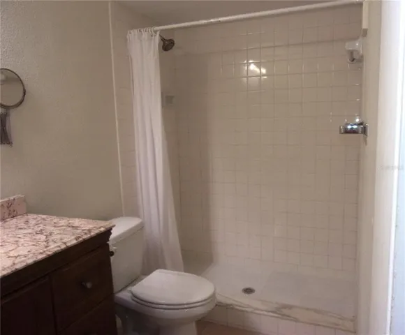 a bathroom with a granite countertop toilet and a shower