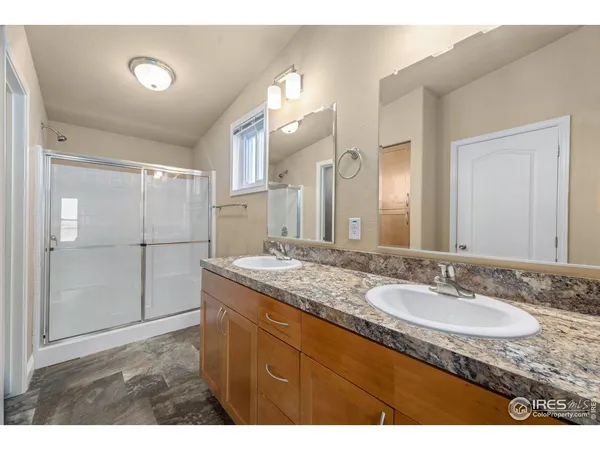a bathroom with a granite countertop sink a mirror and shower