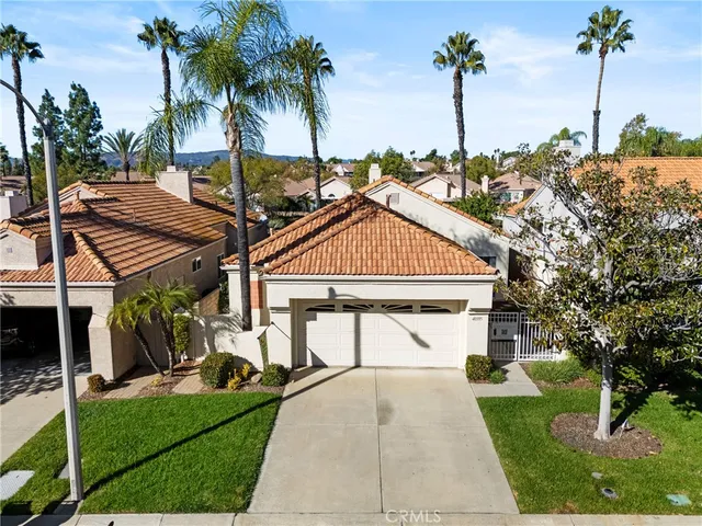 a view of multiple houses with a yard and palm trees