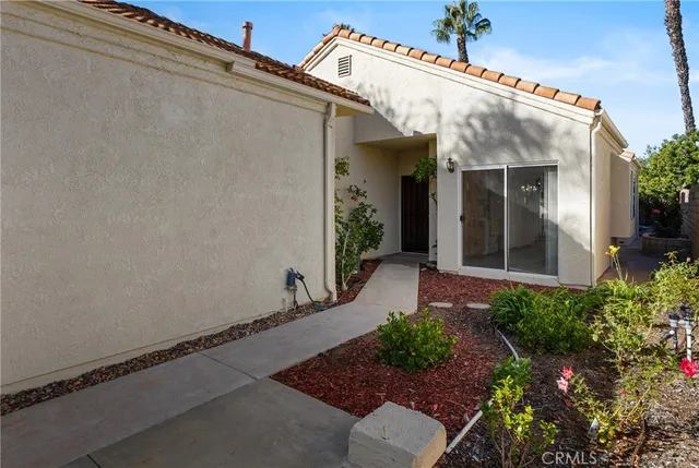a view of a house with a small yard plants and floor to ceiling window