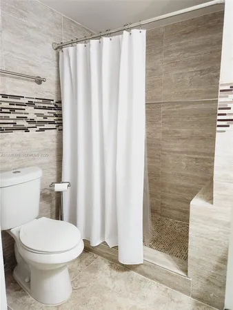 a white toilet sitting next to a shower curtain