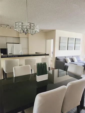 a living room with furniture a chandelier and kitchen view