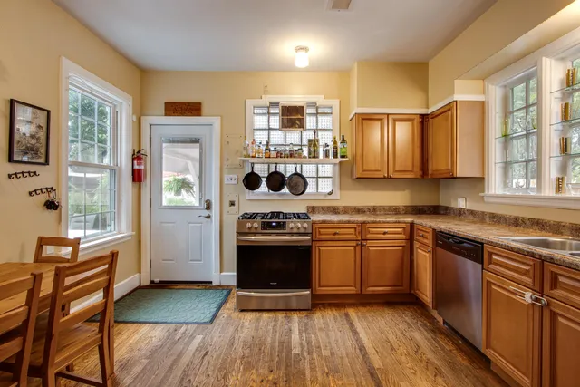 a kitchen with stainless steel appliances granite countertop hardwood floor sink stove and wooden cabinets