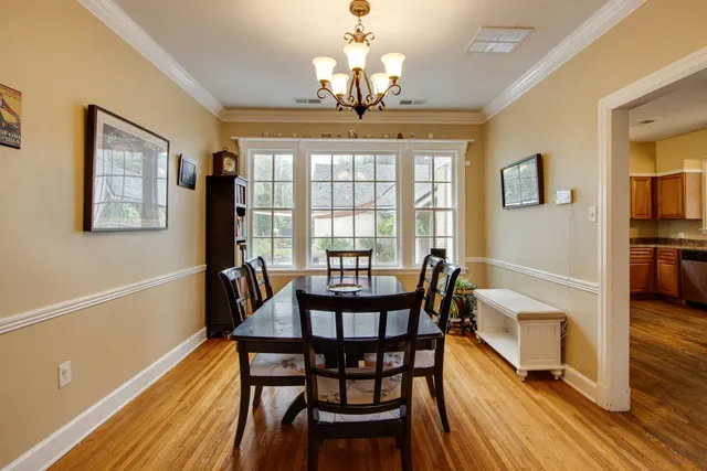 a dining room with wooden floor a chandelier a wooden table and chairs