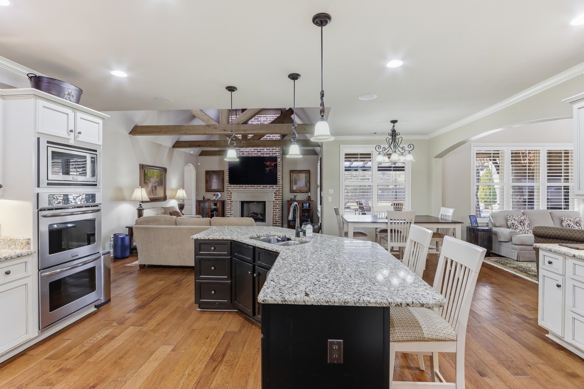 1301 Conser Street Collierville, TN 38017 - Photo 13 of 40 a open kitchen with granite countertop a stove top oven a sink dishwasher a dining table and chairs with wooden floor