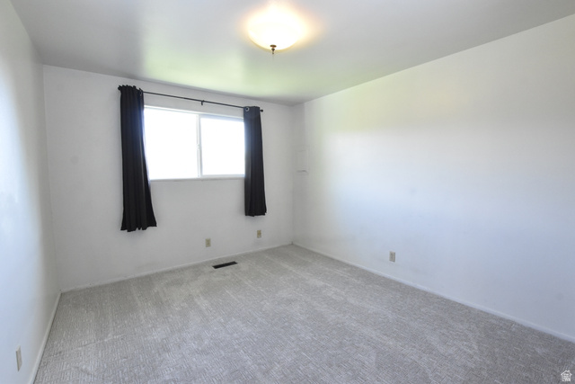 290 West 600 North Logan, UT 84321 - Photo 31 of 45 Bright interior space featuring a window with dark drapes, light-colored carpeting, white wall finishes, and a flush-mount ceiling light fixture