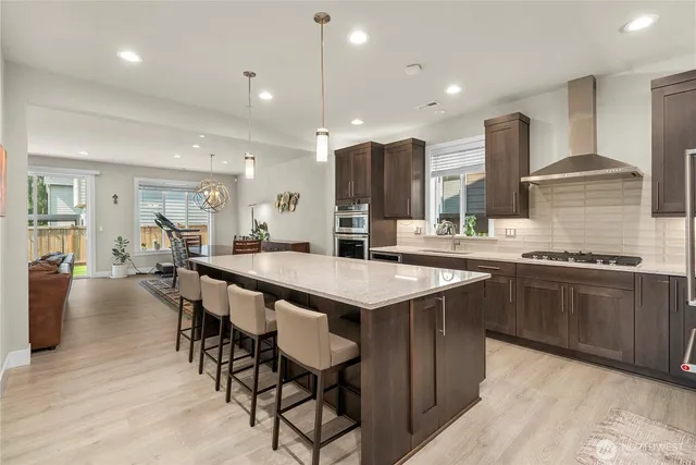 a kitchen with stainless steel appliances kitchen island granite countertop a table chairs sink and cabinets