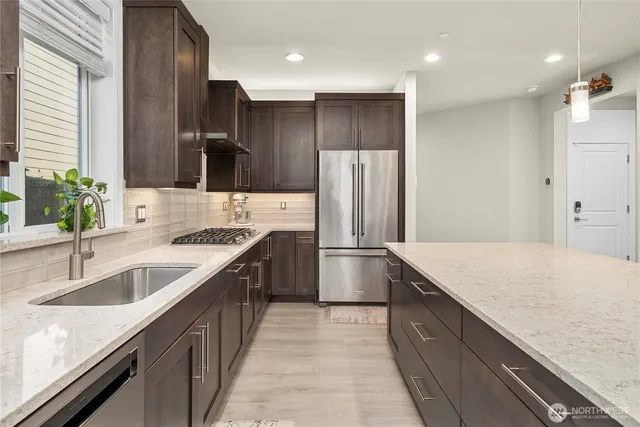 a kitchen with stainless steel appliances granite countertop a sink and a refrigerator