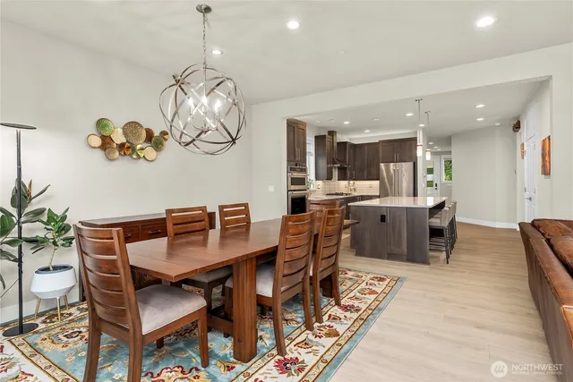a dining room with wooden floor a chandelier a wooden table and chairs