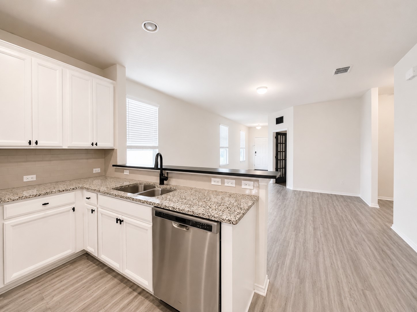 220 Pepperbark Loop Buda, TX 78610 - Photo 12 of 27 Polished granite countertops and classic white cabinetry define this open-concept kitchen space.