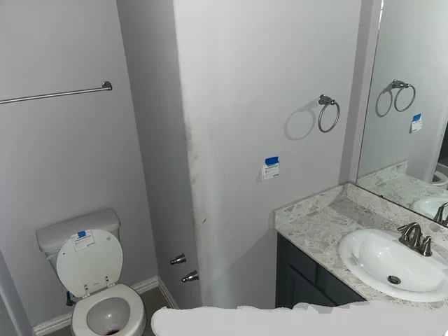 a bathroom with a granite countertop sink toilet and mirror