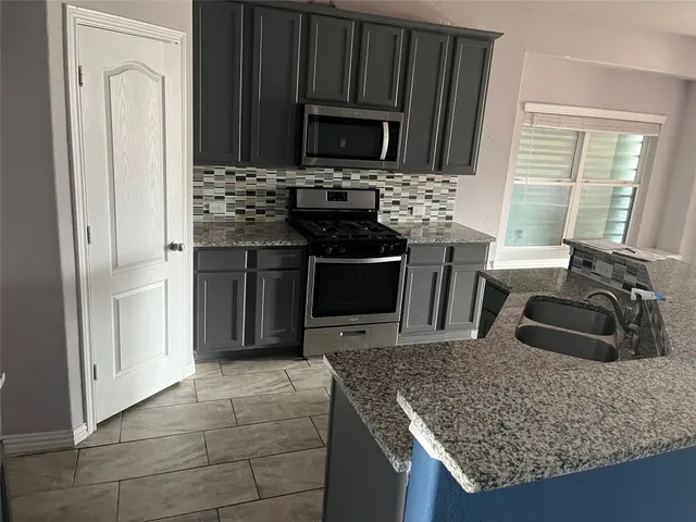 a kitchen with stainless steel appliances granite countertop a stove refrigerator and microwave