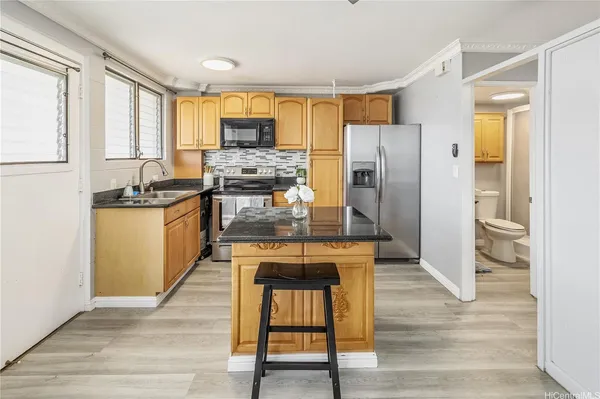 a kitchen with granite countertop a refrigerator stove top oven and sink