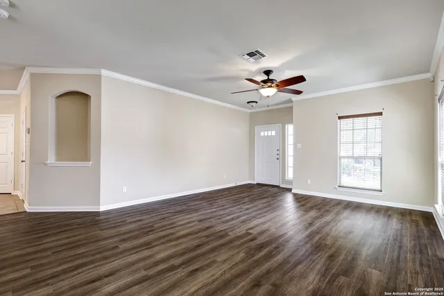 a view of an empty room with wooden floor and a window