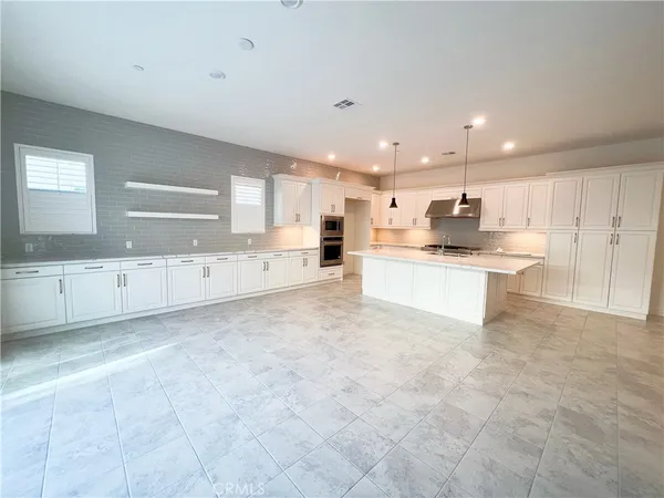 a large white kitchen with a stove a sink a refrigerator and white cabinets with wooden floor