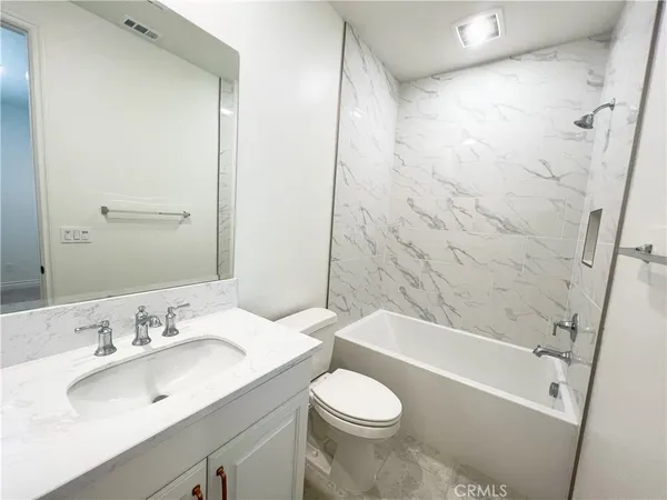 a bathroom with a granite countertop sink toilet and shower
