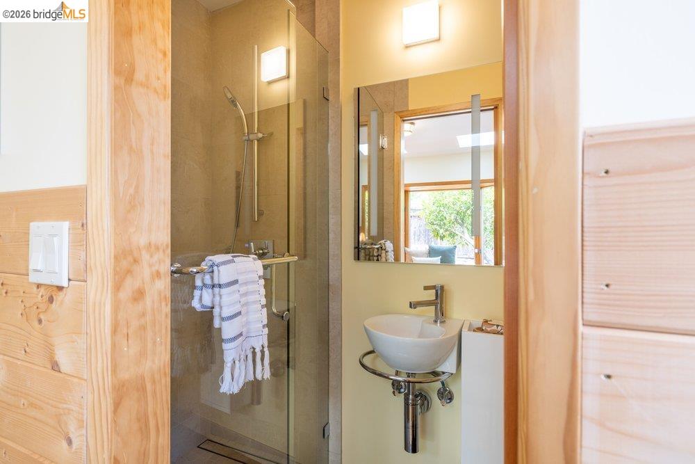 287 Purdue Avenue Kensington, CA 94708 - Photo 53 of 60 Modern bathroom featuring a glass-enclosed shower with tile surround, a vessel sink with chrome fixtures, and a framed mirror