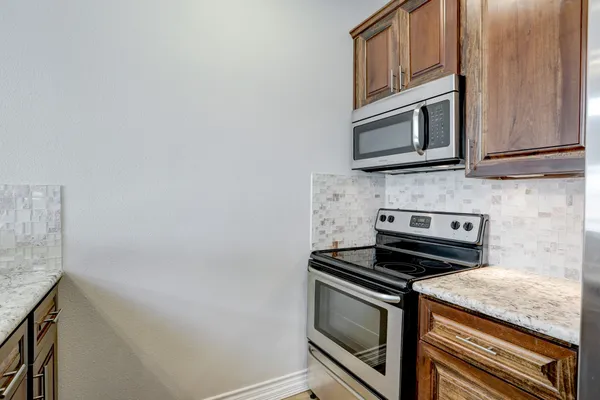 a kitchen with granite countertop cabinets stove and microwave