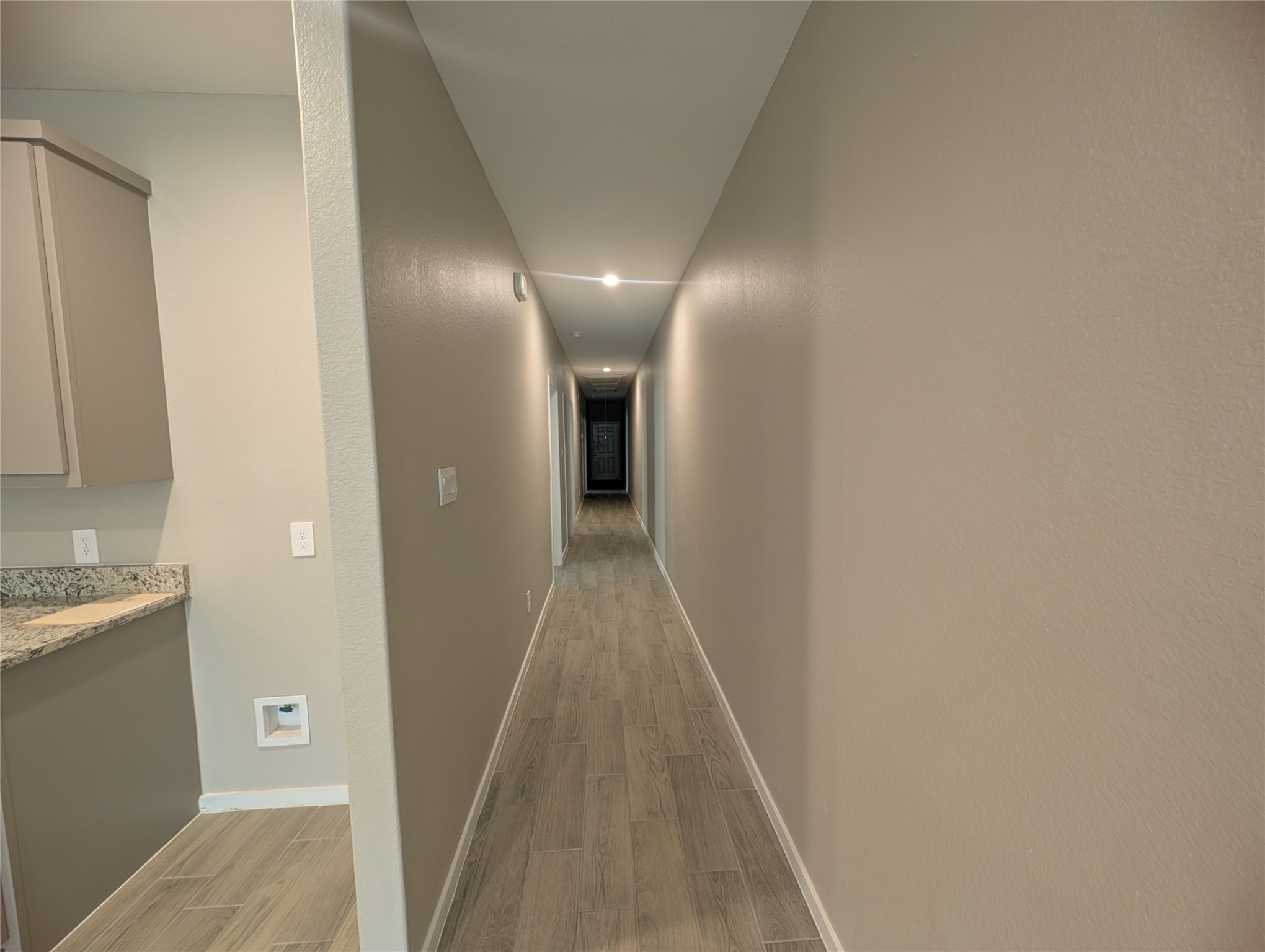 7745 Swiftwater Lane, Unit A Houston, TX 77075 - Photo 12 of 33 This long, illuminated hallway connects the main living area to the private rooms, featuring the same cohesive grey wood-look tile flooring and neutral tan walls seen throughout the home, creating a clean, modern, and unified aesthetic.