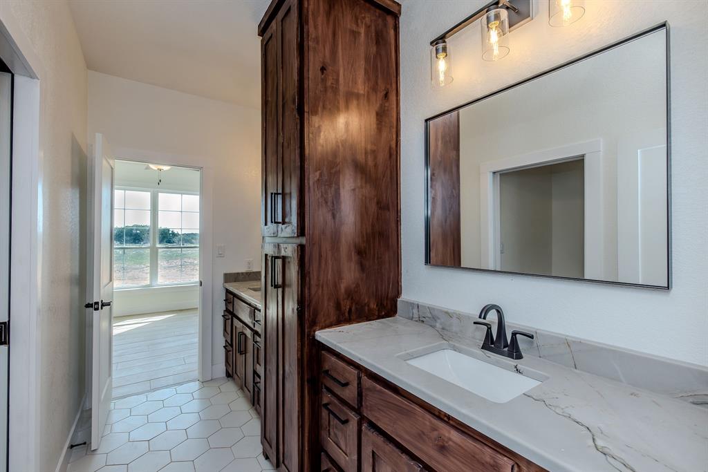 2847 Canyon Wren Loop Graford, TX 76449 - Photo 32 of 40 a en suite bathroom with a granite countertop sink and a mirror