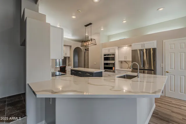 a kitchen with stainless steel appliances kitchen island granite countertop a dining table chairs and a refrigerator