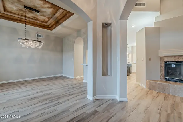 an empty room with wooden floor a fireplace and windows