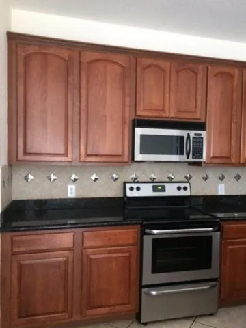 a kitchen with granite countertop wood cabinets and stainless steel appliances