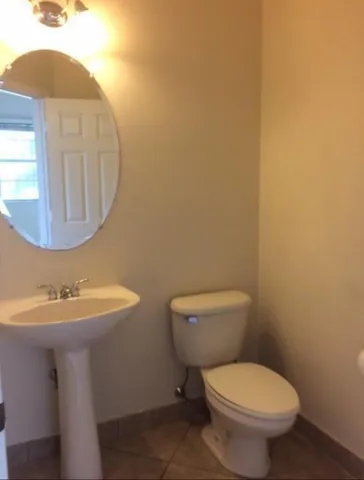 a bathroom with a toilet a sink and mirror