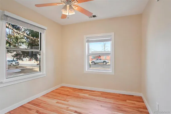 a view of an empty room with wooden floor and a window