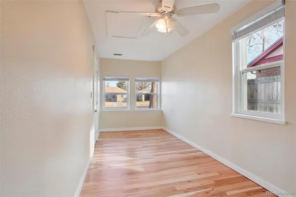 a view of an empty room with a window and wooden floor