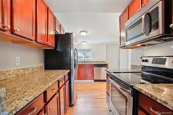 a kitchen with stainless steel appliances granite countertop a sink and dishwasher stove a refrigerator with wooden cabinets