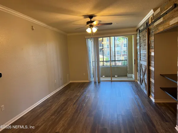 a view of an empty room with a window and wooden floor