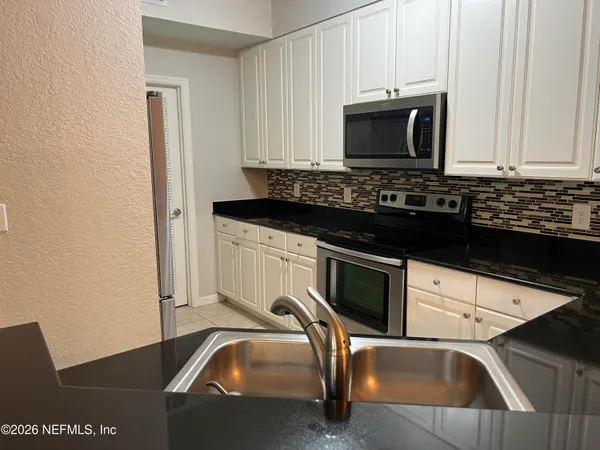 a kitchen with granite countertop a stove and a microwave