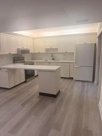 a large kitchen with cabinets a sink and dishwasher a stove with wooden floors