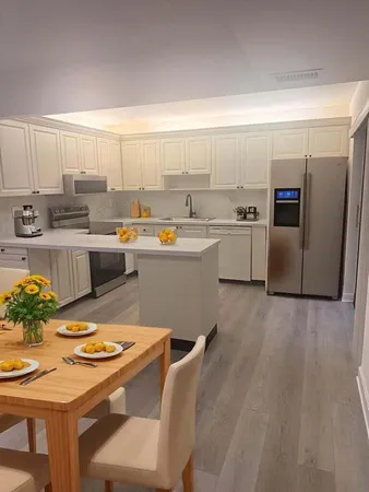 a kitchen with stainless steel appliances granite countertop a sink a stove a refrigerator a microwave oven with white cabinets and wooden floor