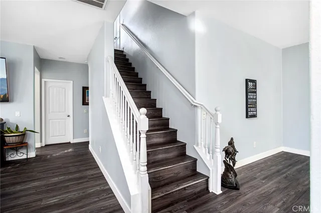 a kitchen with stainless steel appliances granite countertop a sink dishwasher a stove and a refrigerator with wooden floor