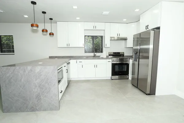 a large kitchen with stainless steel appliances granite countertop a stove a sink and a refrigerator