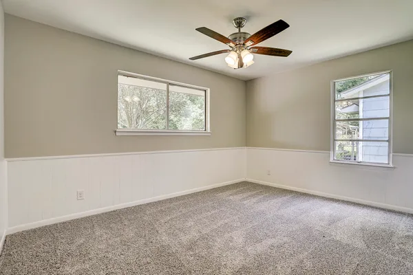 an empty room with windows and fan